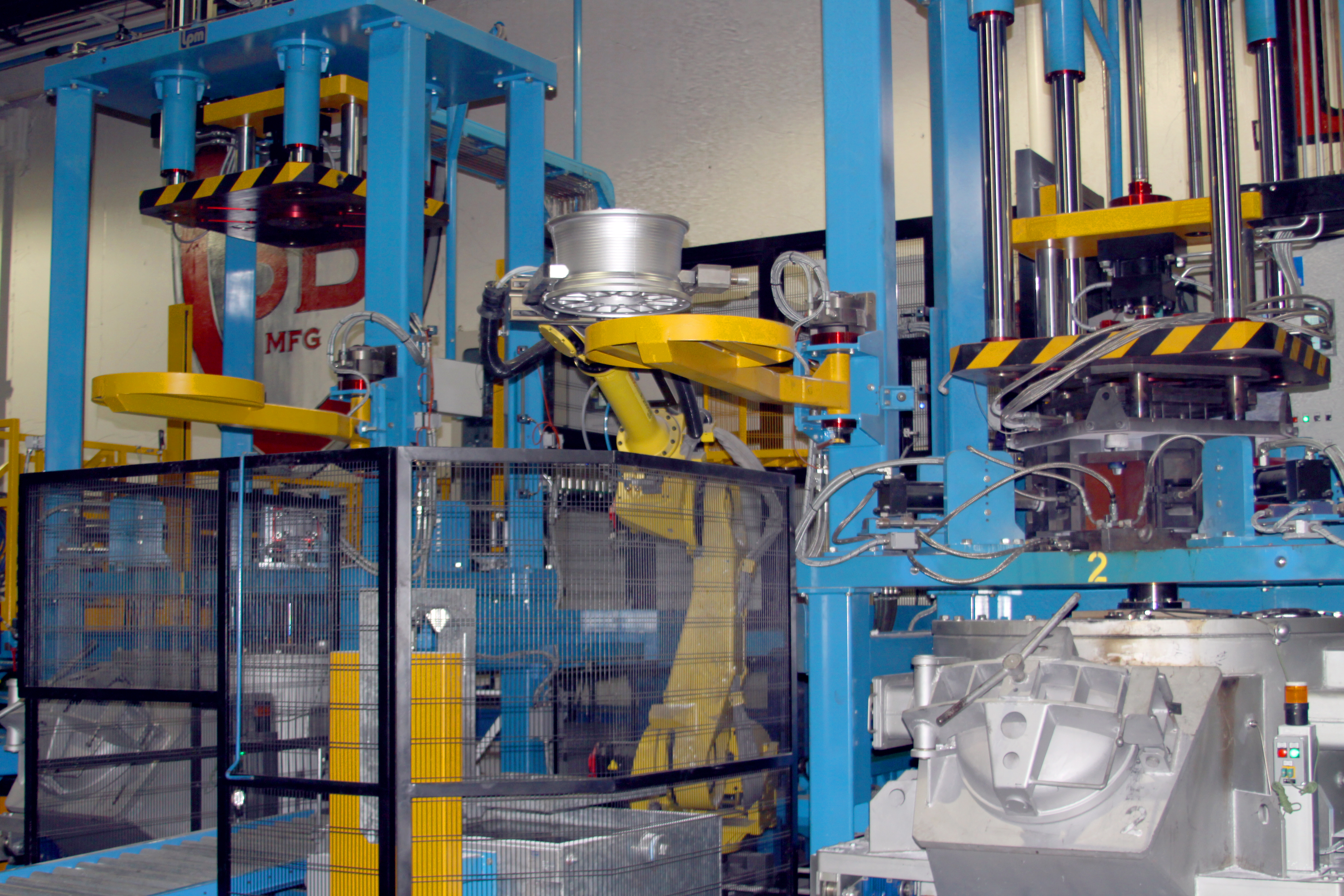 a yellow robotic arm moves a freshly cast wheel from the casting machine into a cooling bath.