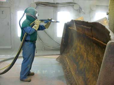 Sandblasting a bulldozer blade
